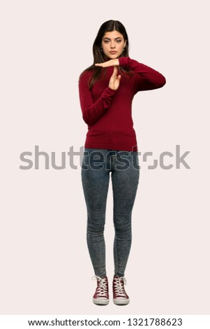 A full-length shot of a Teenager girl with turtleneck making time out gesture over isolated background