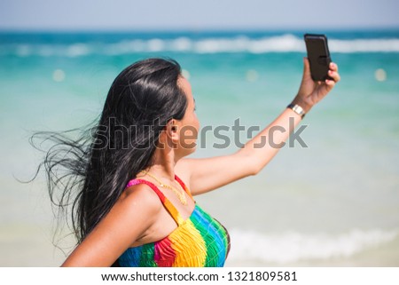Beautiful young asian woman is taking a selfie while standing at the beach