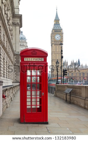 Traditional red telephone box in London public phone - a symbol of the city. Fragment of booths with the Big Ben in the background of the evening