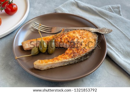 Fried salmon served on plate with caper apples.