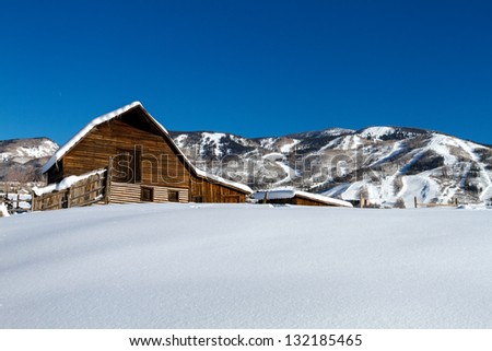 Historic Steamboat Springs barn on snowy hill with ski area lifts and slopes in background