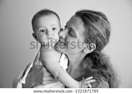 Beautiful young mother holding infant baby girl. Black and white family photography.
