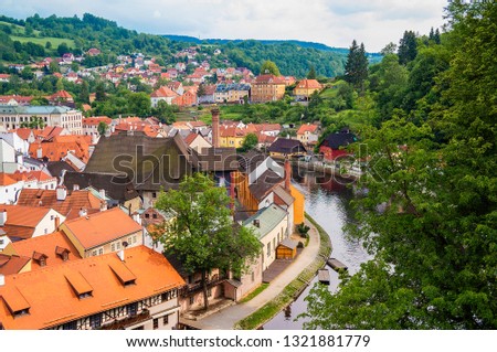 Cescy Krumlov historic center summer view. Cozy small European town with tiled red roofs. Gorgeous river Vltava bend sight with green trees,  and tile roof historic river front houses of old town.