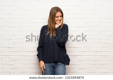 Blonde woman over brick wall with toothache