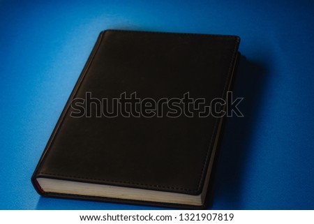 black notebook with white pages on blue background