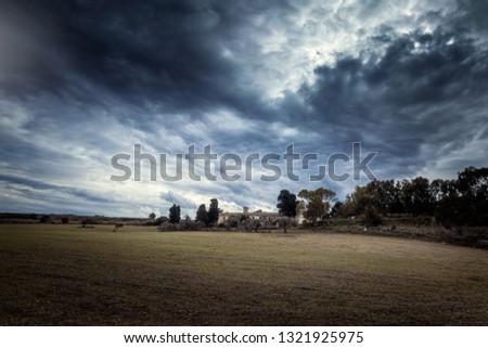 Cloudy mood over sicilian fields. Old hermitage church in the center.
