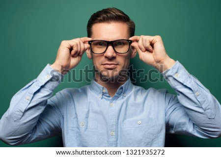Young handsome guy office manager or businessman in formal wear and eyeglasses against green background.