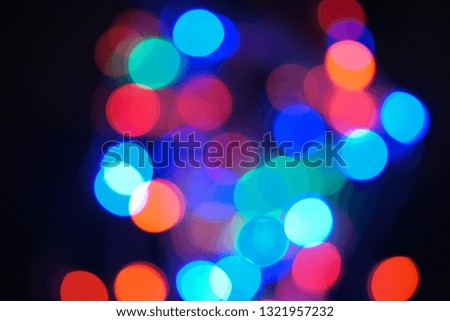 Multi-color blue holiday garland. Garland is blurred. Many big colorful round lights. Fully defocused photo. Blurred background and foreground. Holiday mood. New Year and Christmas is coming.