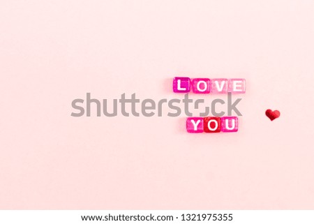 Love you  inscription made of colorful cube beads with letters. Festive pink background concept with copy space
