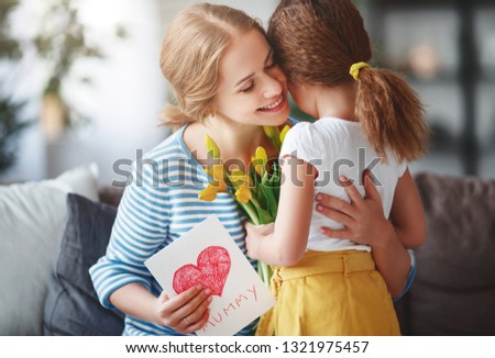 Happy mother's day! Child daughter congratulates moms and gives her a postcard  and yellow flowers  tulip 
