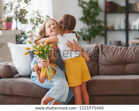 Happy mother's day! Children congratulates moms and gives her a gift and flowers tulips
