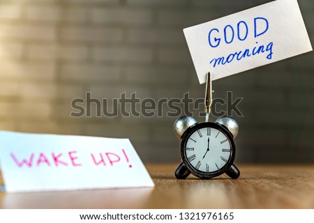 Alarm clock and banner with handwritten phrase"good morning" on wooden table. Time management concept.  