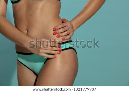 Woman in turquoise panties with red nails on a turquoise background.