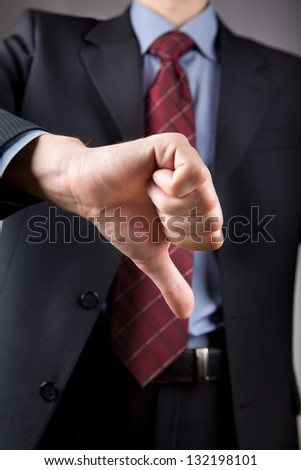 Well-dressed businessman showing disapproval thumbs down sign