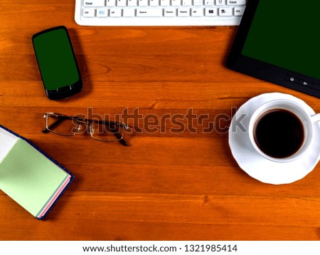 cup with coffee, office supplies and gadgets with a green screen. View from above