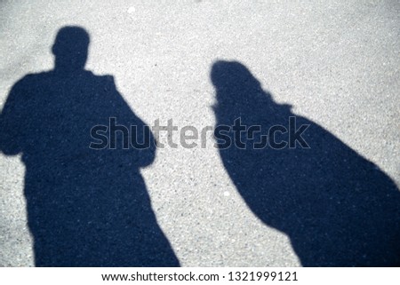 shadow of two people on the pavement