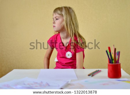 Little girl draws Beautiful little girl drawing lesson. The child draws in his room. The little girl looks sad.