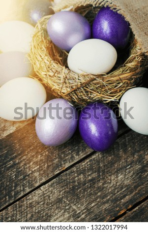 Bright purple colored Easter eggs in nest on wooden background, selective focus image. Happy Easter card 