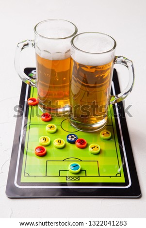 Picture of two mugs of frothy beer, table football