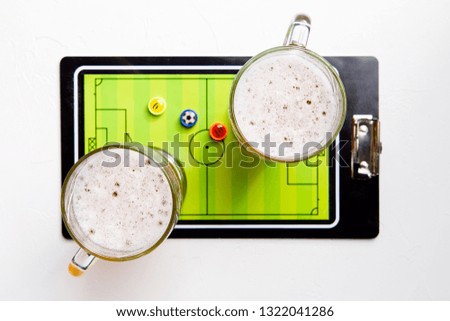 Picture on top of two mugs of frothy beer, table football