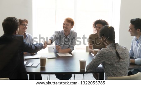 Happy businessmen shake hands at diverse group meeting negotiations make deal thank for teamwork sign contract, smiling young male workers handshaking greeting as respect, business agreement concept