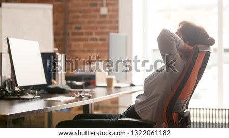 Calm businesswoman office worker holding hands behind head finished computer work at workplace relaxing sitting in ergonomic chair taking break rest feel no stress relief balance having healthy nap Royalty-Free Stock Photo #1322061182
