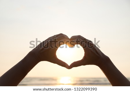 "Love sign", hand heart symbol in afternoon sunset sky.
