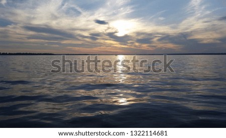 Amazing scenic landscape of a beginning of a sunset on an ocean. Colorful cloudy sky is reflecting in slight dark navy waves with yellow solar track on it.