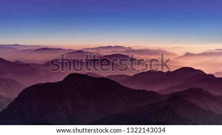 View of Himalayas mountain range with visible silhouettes through the colorful fog from Khalia top trek trail. Khalia top is at an altitude of 3500m himalayan region of Kumaon, Uttarakhand, India. Royalty-Free Stock Photo #1322143034
