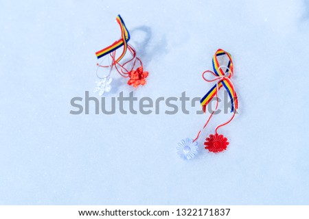 Martisor with romanian tricolor elements on snow texture background. Moldavian and Romanian spring symbol. Martisor is a red and white string which is offered by people on March 1 as love talisman. 