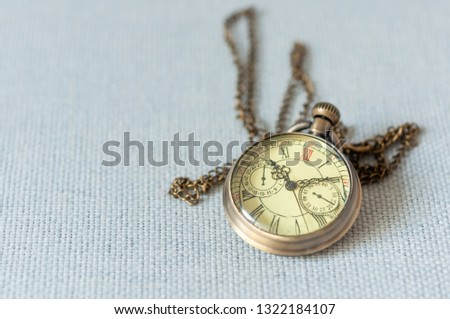 Golden vintage pocket watch with long strap on gray background, pocket watch time clock 10:10.