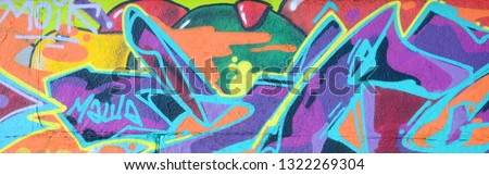 Fragment of graffiti drawings. The old wall decorated with paint stains in the style of street art culture. Multicolored background texture Royalty-Free Stock Photo #1322269304