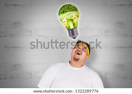 Picture of happy fat man getting an idea while looking at vegetables shaped a bulb