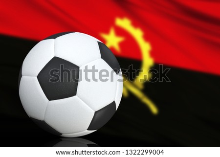 Soccer black and white ball close up, in the background a blurred flag of Angola. The image takes place for your text.