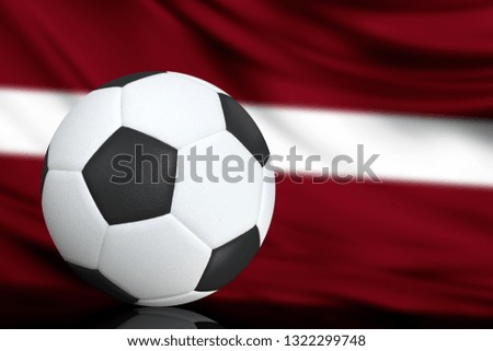 Soccer black and white ball close up, in the background a blurred flag of Latvia. The image takes place for your text.