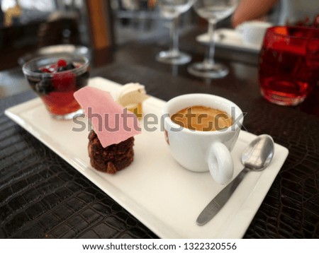sweet two cakes with chocolate on plate and cup of coffee on table - Image