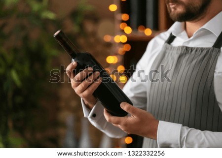 Barman with bottle of wine, closeup