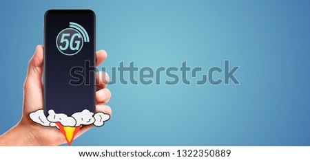 male hand hold launching 5G smartphone, on blue background.