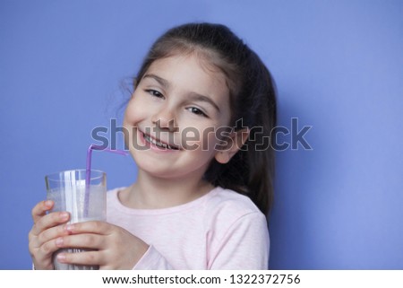 Happy little girl drinking a milk cocktail. Adorable child with milkshake.
