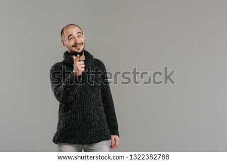 young and happy man, raised his index finger and looking at the camera, isolated on gray background. Concept of the idea or warning 
