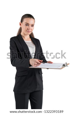 Isolated portrait of serious young businesswoman in black suit holding clipboard and pen and giving it to you to sign