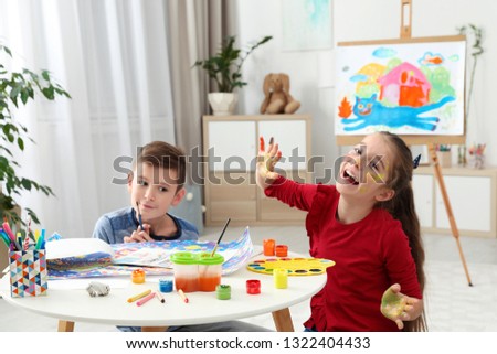 Happy children having fun with paints together at table indoors