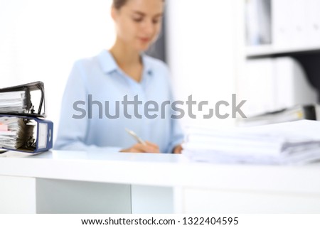 Binders with papers are waiting to be processed by business woman or bookkeeper back in blur. Internal Audit and tax concept