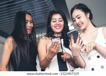 Three women friends having conversation while looking at mobile phone in their hands. Concept of social media, gossip news and online shopping.