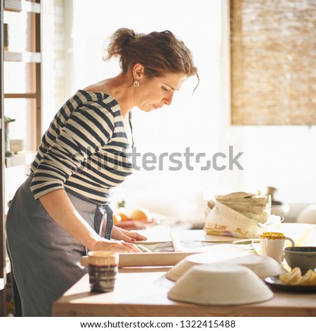 Beautiful happy  woman making ceramic ware in workplace in sun light. Concept for woman in freelance, business, hobby