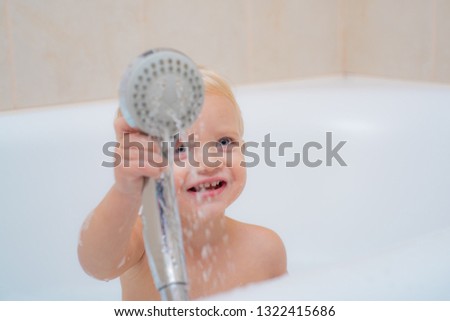 Bathroom. Little baby washing with a bubbles in bath in a hat. Cute little boy washing. Child in clean and dry towel
