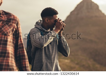 Man taking pictures during a hike with friends. Social media influencer capturing new content of this social media during a hike.