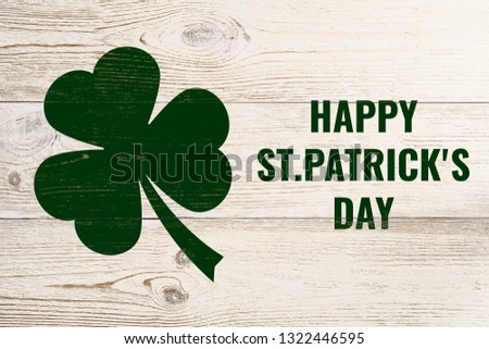 happy st. patrick's day, green text and clover leaf over white wooden wall