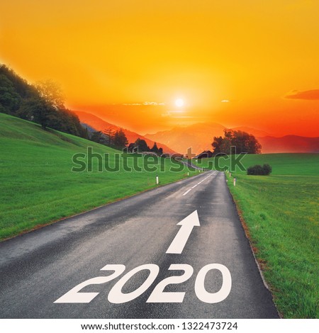 Driving on idyllic open road against the setting sun forward on goals in the mountains to new year 2020. Concept for success, passing time and future. Empty asphalt road.