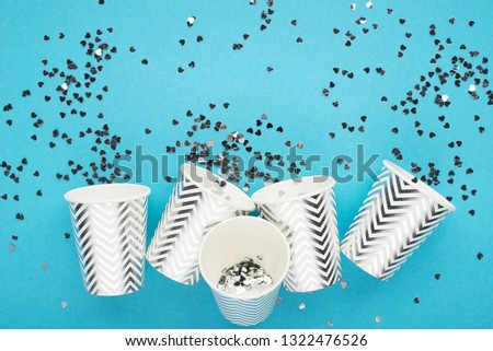 Universal festive blue background with silver confetti and glitter with paper cups. The main trend concept is no plastic on a clean planet. Horizontal, space for text